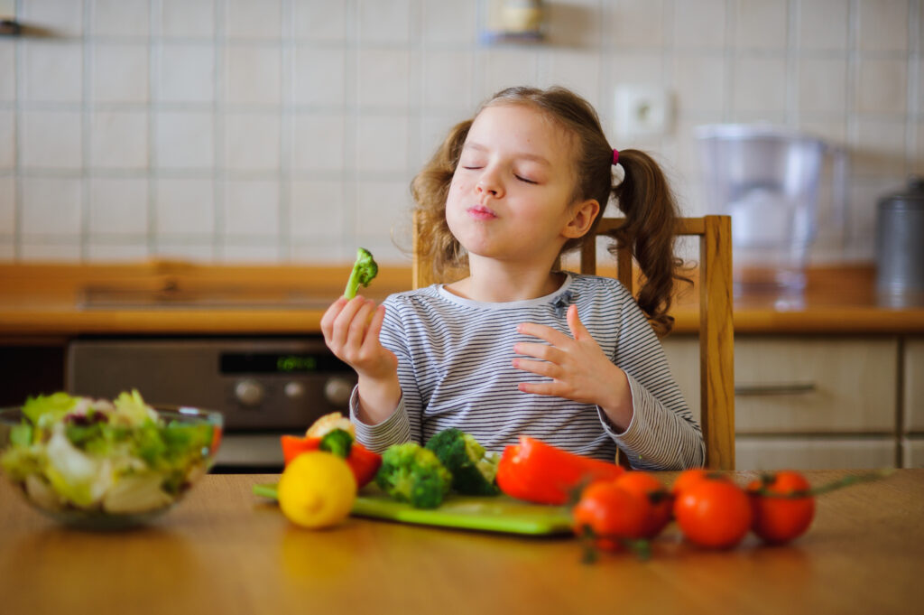 Una niña pequeña come brócoli y le mucho. Las emociones juegan un papel importante en la alimentación.